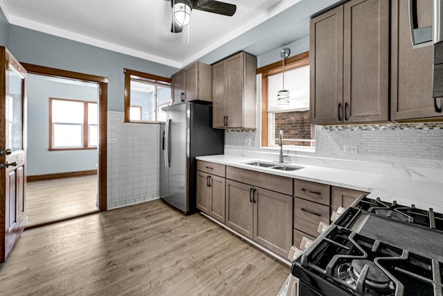 kitchen featuring pendant lighting, a healthy amount of sunlight, sink, and stainless steel refrigerator with ice dispenser