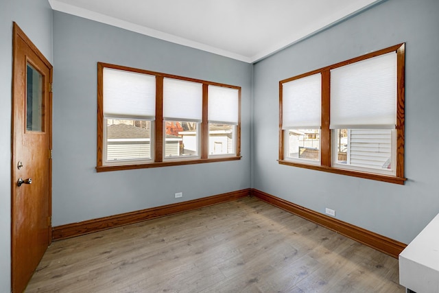 empty room with crown molding and light wood-type flooring