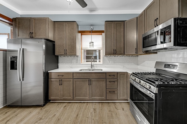 kitchen featuring pendant lighting, sink, light hardwood / wood-style flooring, ceiling fan, and stainless steel appliances