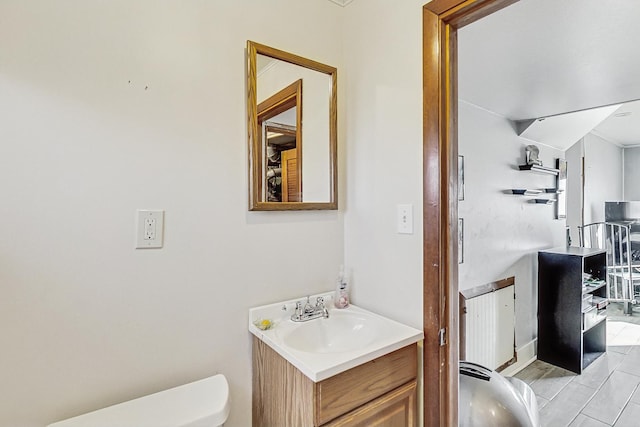 half bath featuring radiator heating unit, vanity, and toilet