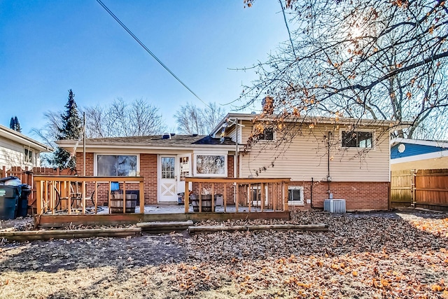 rear view of house featuring brick siding, fence, a deck, and central air condition unit