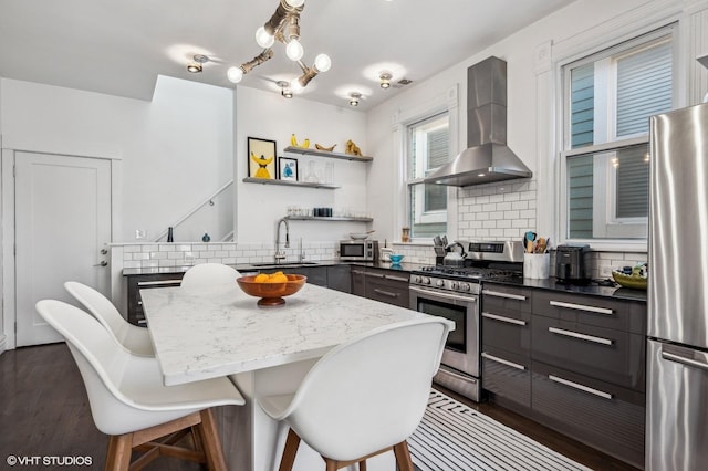 kitchen featuring sink, stainless steel appliances, a center island, tasteful backsplash, and wall chimney exhaust hood