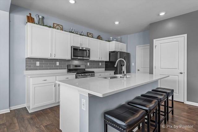 kitchen with white cabinetry, appliances with stainless steel finishes, a kitchen island with sink, and a breakfast bar area