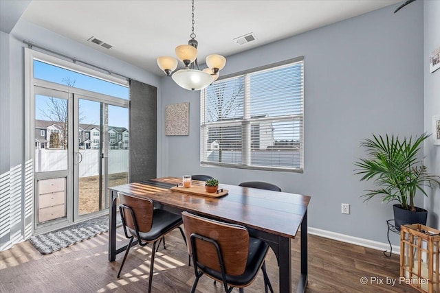 dining room with an inviting chandelier, dark wood-type flooring, and a healthy amount of sunlight