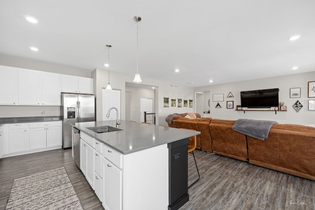 kitchen with appliances with stainless steel finishes, open floor plan, a sink, and dark wood-style floors