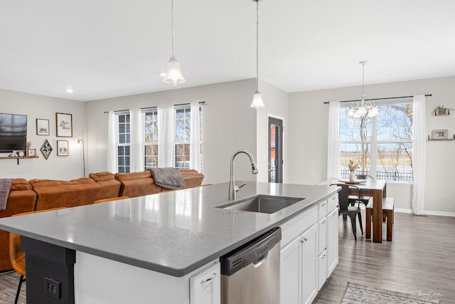 kitchen with a kitchen island with sink, wood finished floors, a sink, open floor plan, and stainless steel dishwasher