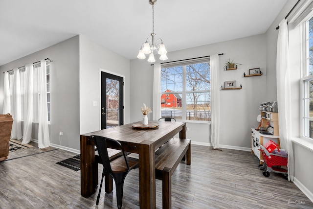 dining space featuring baseboards, wood finished floors, and a notable chandelier