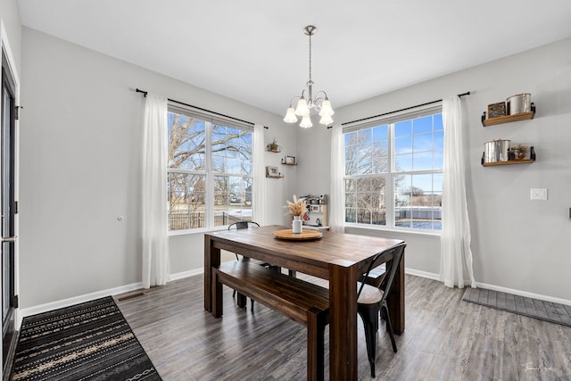 dining area featuring a chandelier, plenty of natural light, baseboards, and wood finished floors