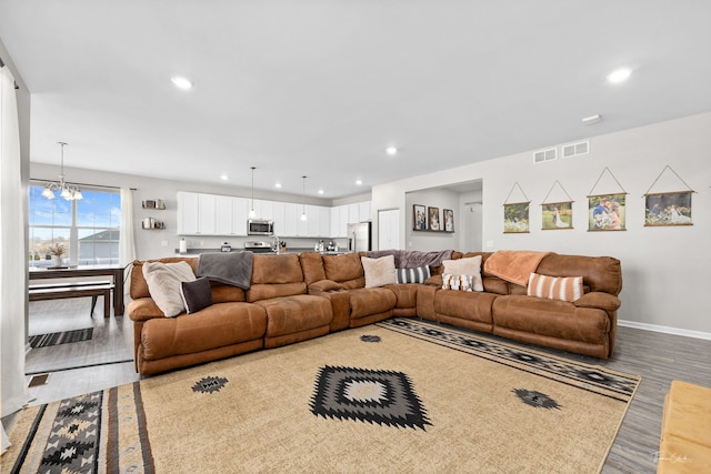 living area with recessed lighting, baseboards, an inviting chandelier, and wood finished floors