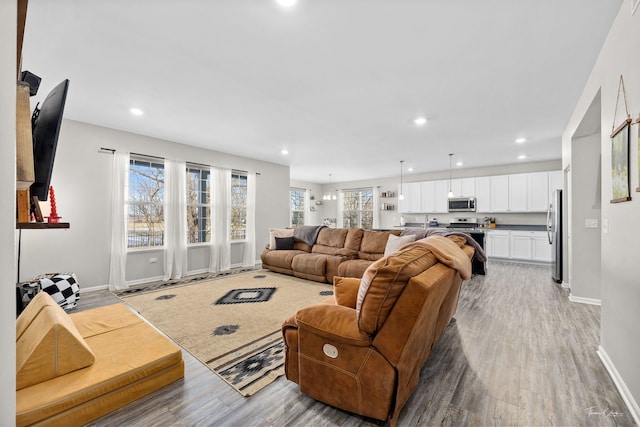 living room featuring light wood finished floors, baseboards, and recessed lighting