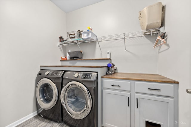 laundry area featuring washer and clothes dryer, wood finished floors, cabinet space, and baseboards