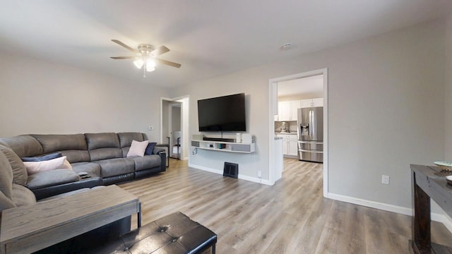 living room with light hardwood / wood-style flooring and ceiling fan