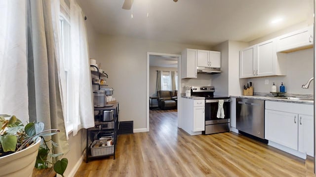 kitchen with sink, white cabinets, stainless steel appliances, light stone countertops, and light wood-type flooring