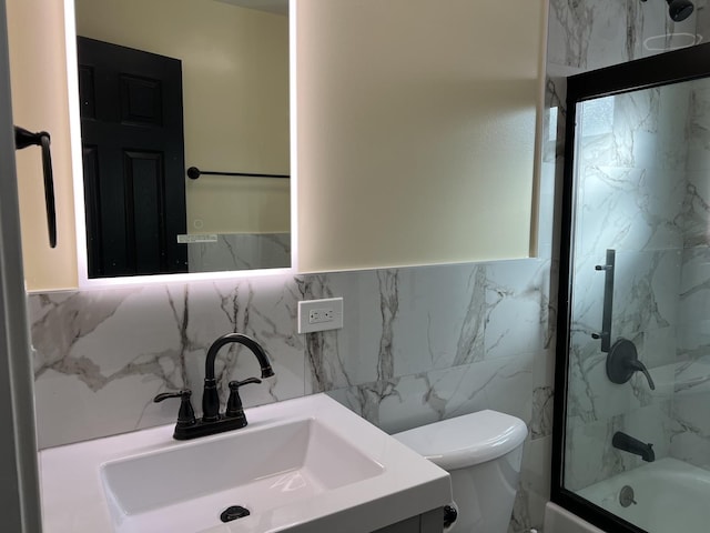 full bathroom featuring tasteful backsplash, vanity, combined bath / shower with glass door, and toilet