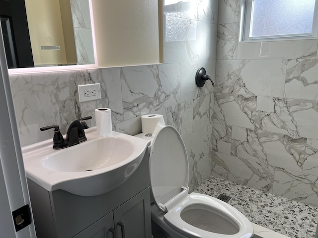 bathroom with tile walls, backsplash, tiled shower, vanity, and toilet