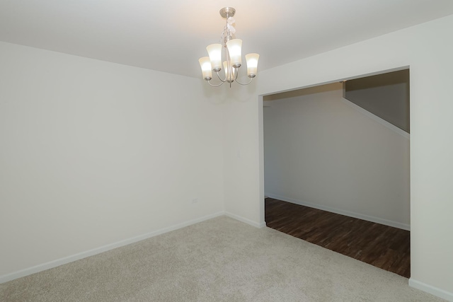 carpeted spare room with a chandelier