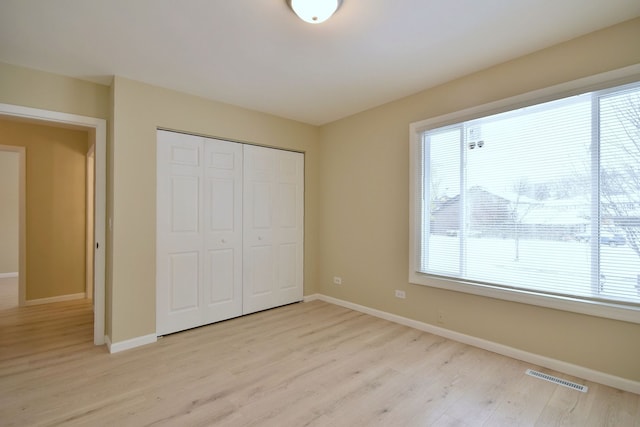 unfurnished bedroom with light wood-type flooring and a closet