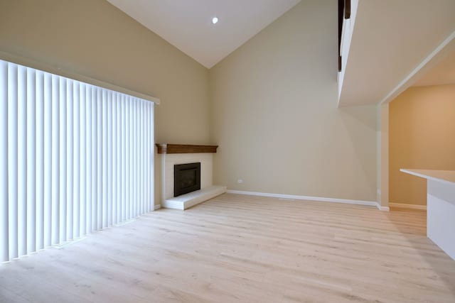 unfurnished living room with high vaulted ceiling and light wood-type flooring