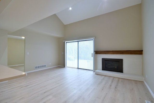 unfurnished living room with a brick fireplace, high vaulted ceiling, and light hardwood / wood-style floors