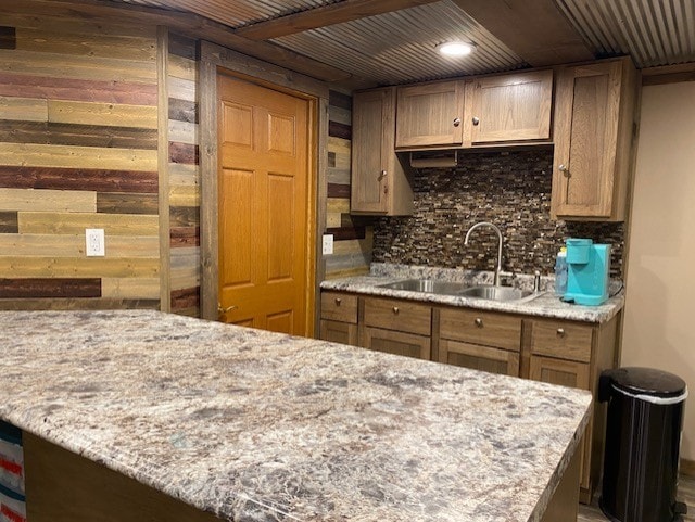 kitchen featuring wood ceiling, a sink, backsplash, and light stone countertops