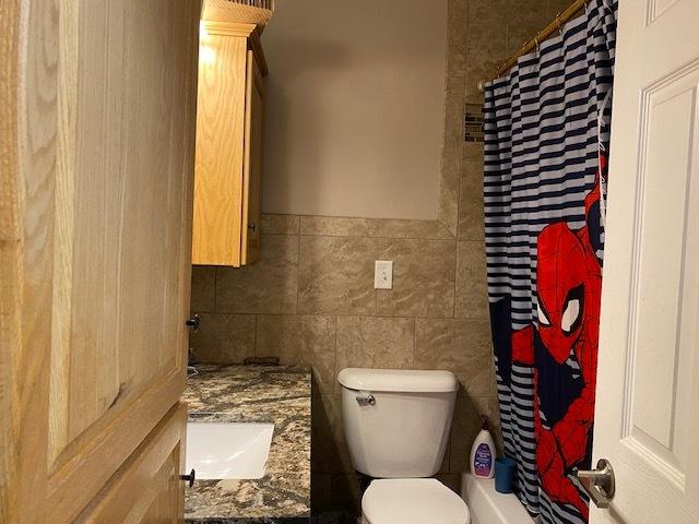 full bathroom with vanity, toilet, and tile walls