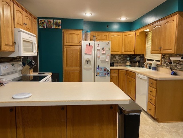 kitchen with tasteful backsplash, light countertops, a peninsula, white appliances, and a sink