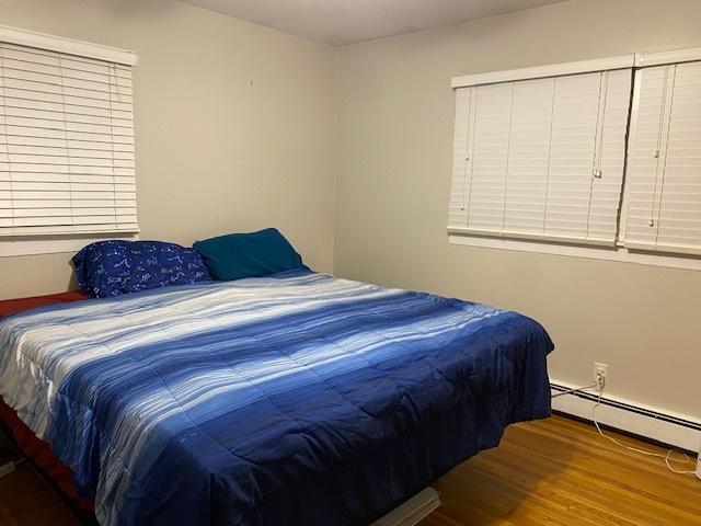 bedroom with a baseboard heating unit and wood finished floors