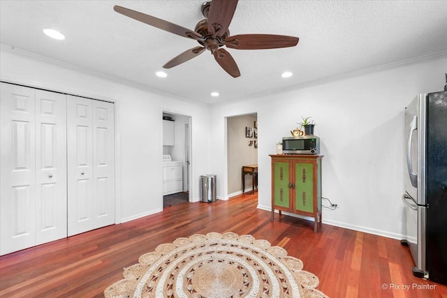 sitting room featuring dark wood-type flooring, washer / dryer, a textured ceiling, ornamental molding, and ceiling fan