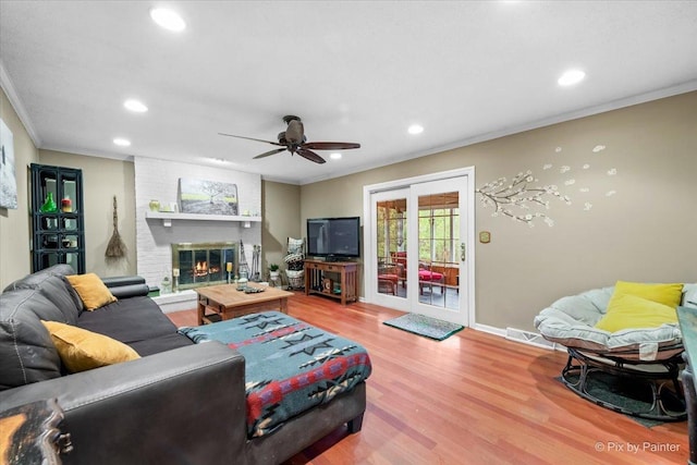 living room featuring ornamental molding, hardwood / wood-style floors, ceiling fan, and a fireplace