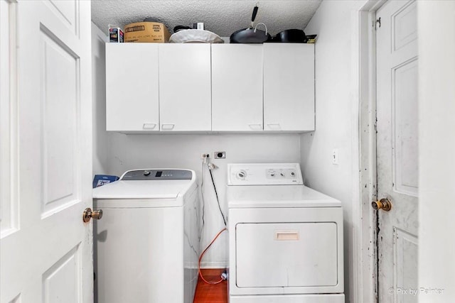 washroom featuring washer and clothes dryer, cabinets, and a textured ceiling