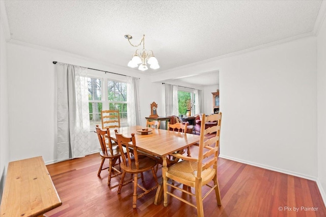 dining area featuring hardwood / wood-style floors, ornamental molding, a chandelier, and a textured ceiling