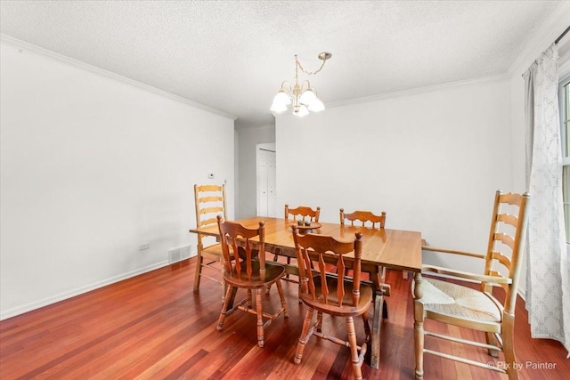 dining area with hardwood / wood-style flooring, crown molding, a notable chandelier, and a textured ceiling