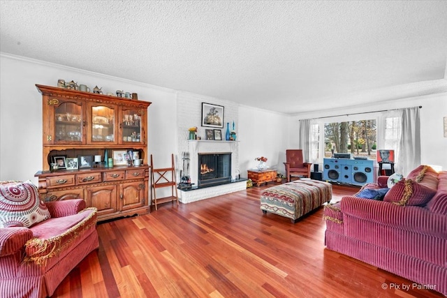 living room featuring a brick fireplace, crown molding, wood-type flooring, and a textured ceiling