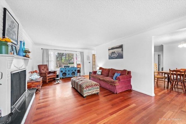 living room featuring crown molding, a brick fireplace, hardwood / wood-style floors, and a textured ceiling