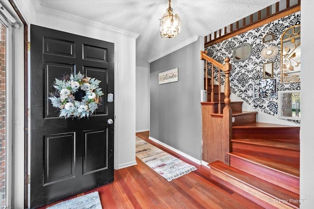 foyer entrance featuring hardwood / wood-style floors, a notable chandelier, ornamental molding, and a textured ceiling