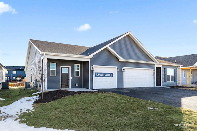 view of front of house featuring a garage, cooling unit, and a front lawn