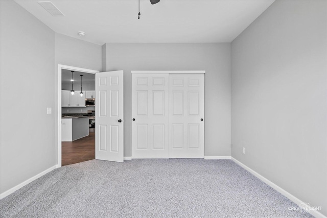 unfurnished bedroom featuring ceiling fan, carpet flooring, and a closet