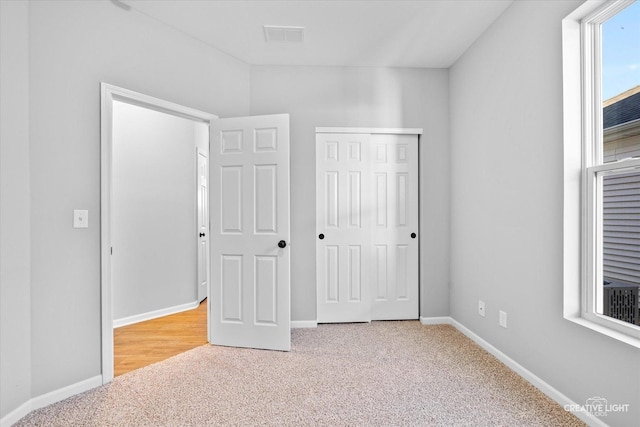 unfurnished bedroom with light colored carpet and a closet