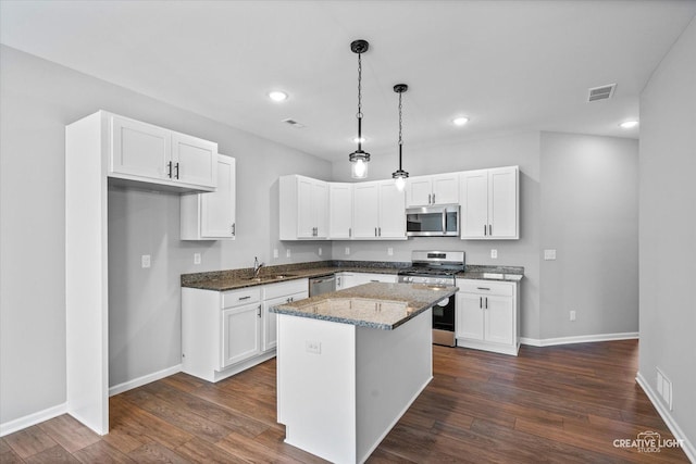 kitchen with dark wood-type flooring, white cabinetry, a center island, dark stone counters, and stainless steel appliances