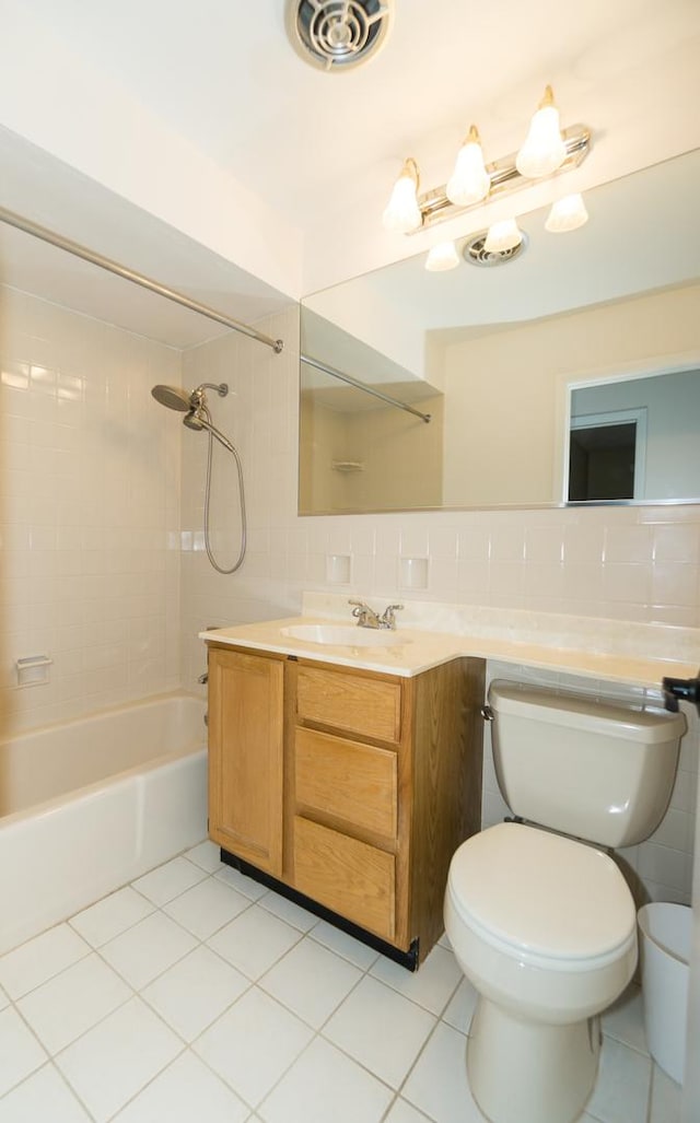 full bathroom with tiled shower / bath, tile patterned floors, toilet, and tile walls