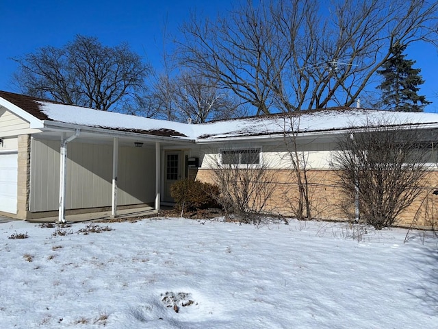 snow covered rear of property with a garage