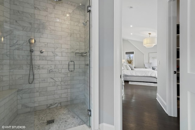 ensuite bathroom featuring baseboards, connected bathroom, wood finished floors, and a stall shower