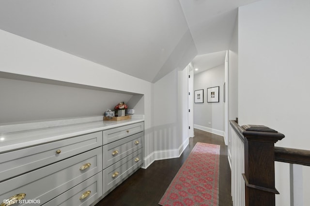 hall with dark wood finished floors, baseboards, and lofted ceiling