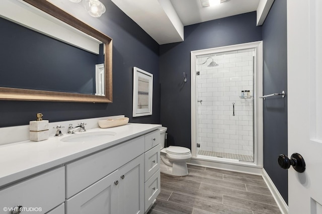 full bathroom featuring vanity, toilet, wood finish floors, and a shower stall