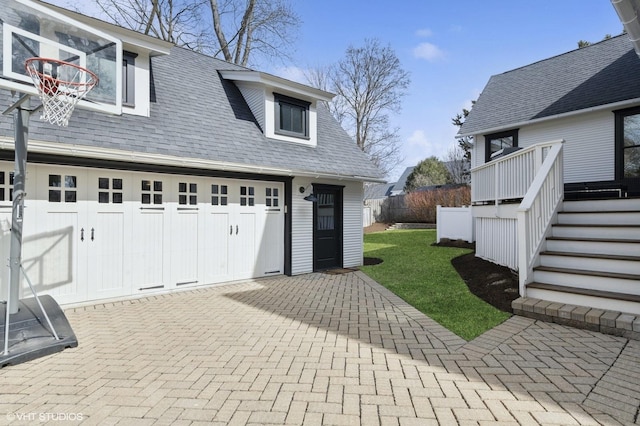 garage featuring decorative driveway and fence