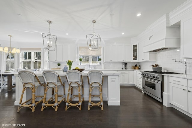 kitchen with a wealth of natural light, premium range hood, an inviting chandelier, and stainless steel range