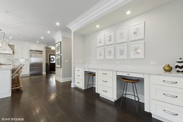 office space with dark wood finished floors, recessed lighting, built in desk, and ornamental molding
