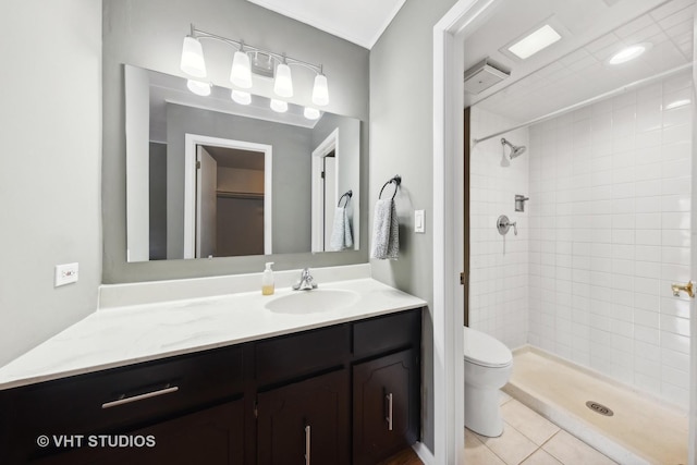 bathroom featuring tiled shower, vanity, toilet, and tile patterned flooring