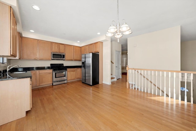 kitchen featuring sink, light wood-type flooring, appliances with stainless steel finishes, a notable chandelier, and pendant lighting