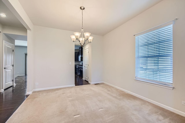 spare room with a notable chandelier and dark carpet